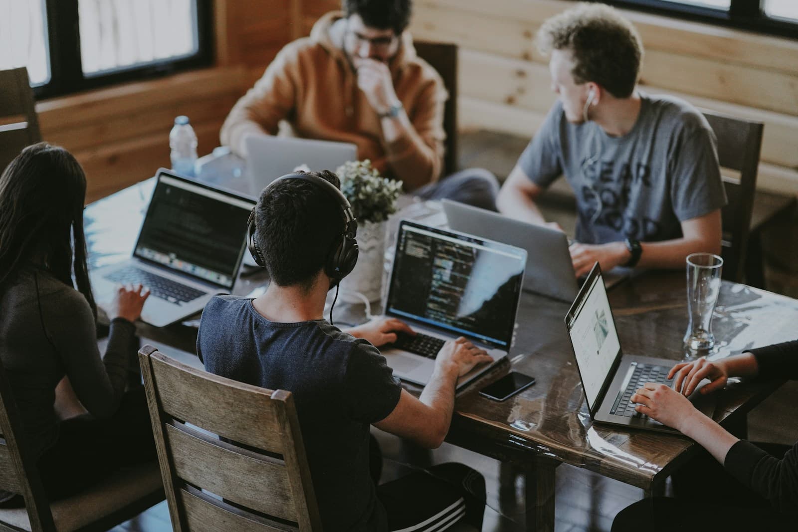 People collaborating around a table with laptops and code on screen